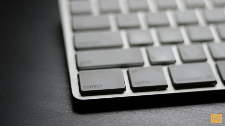 Close-up of an Apple keyboard on a dark surface.