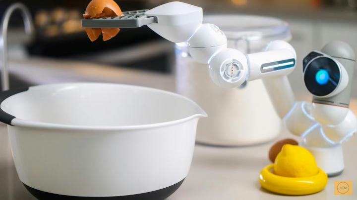 Small white robot holds egg over bowl